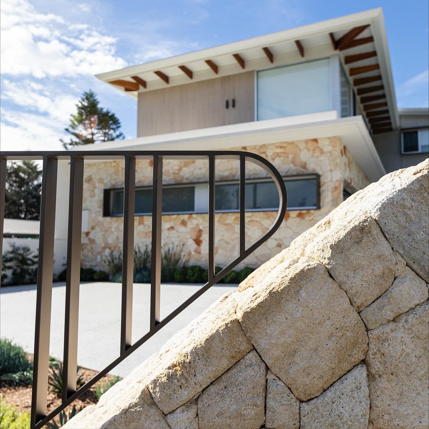 Curved feature gate against sandstone — Avoca Beach House, by J.R Fabrications