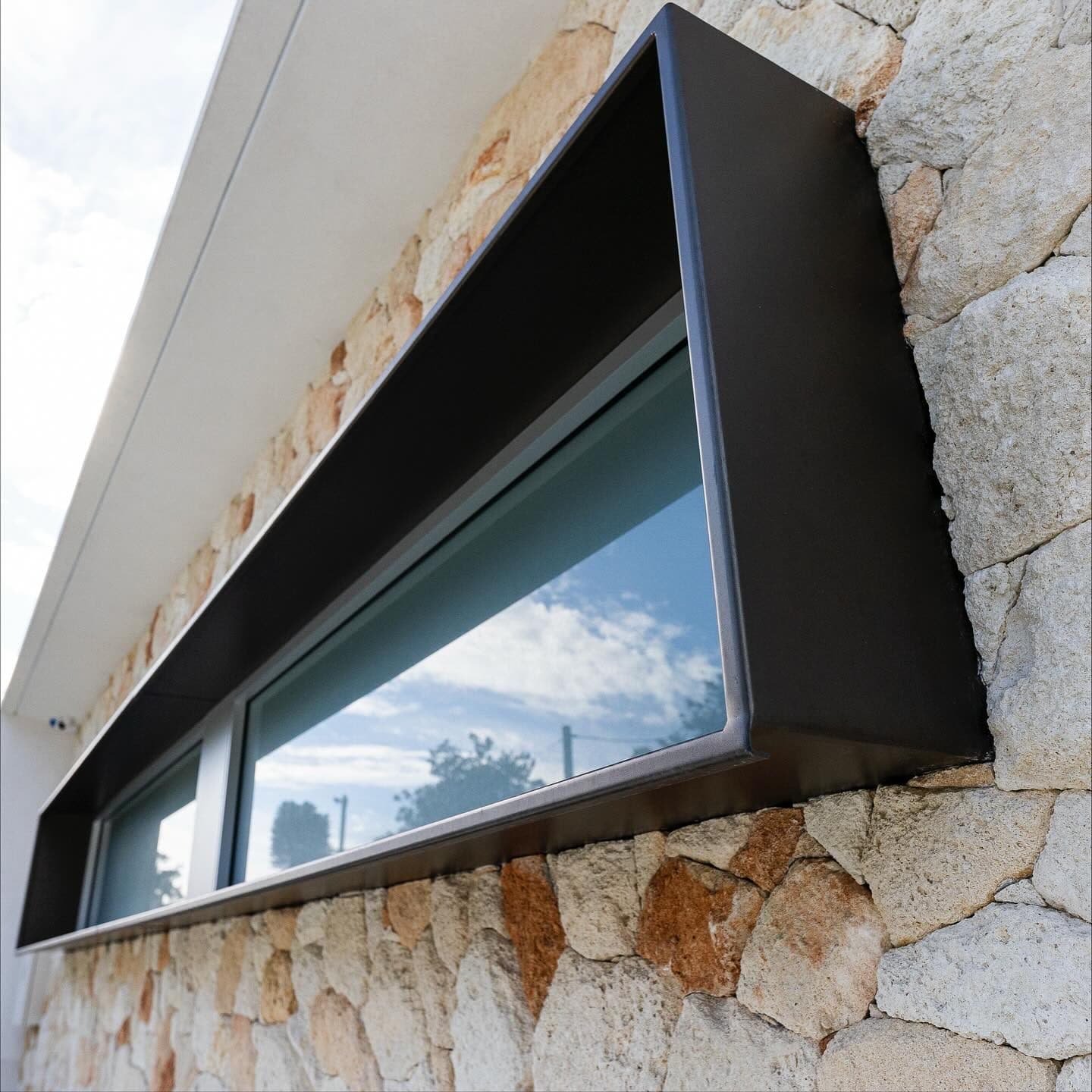 Powder-coated window surround detail against stone