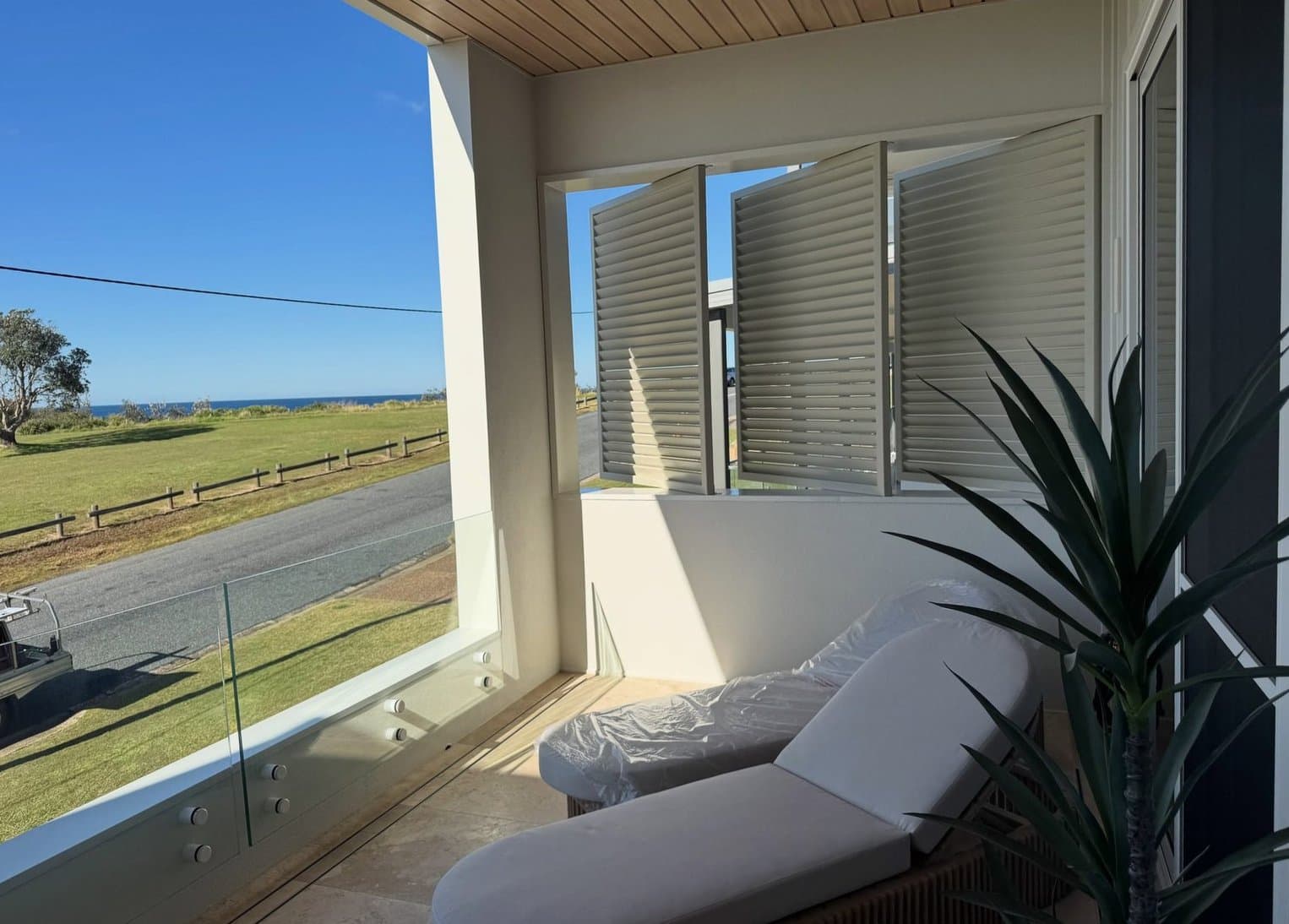 Operable louvre screens filtering ocean light — Caves Beach