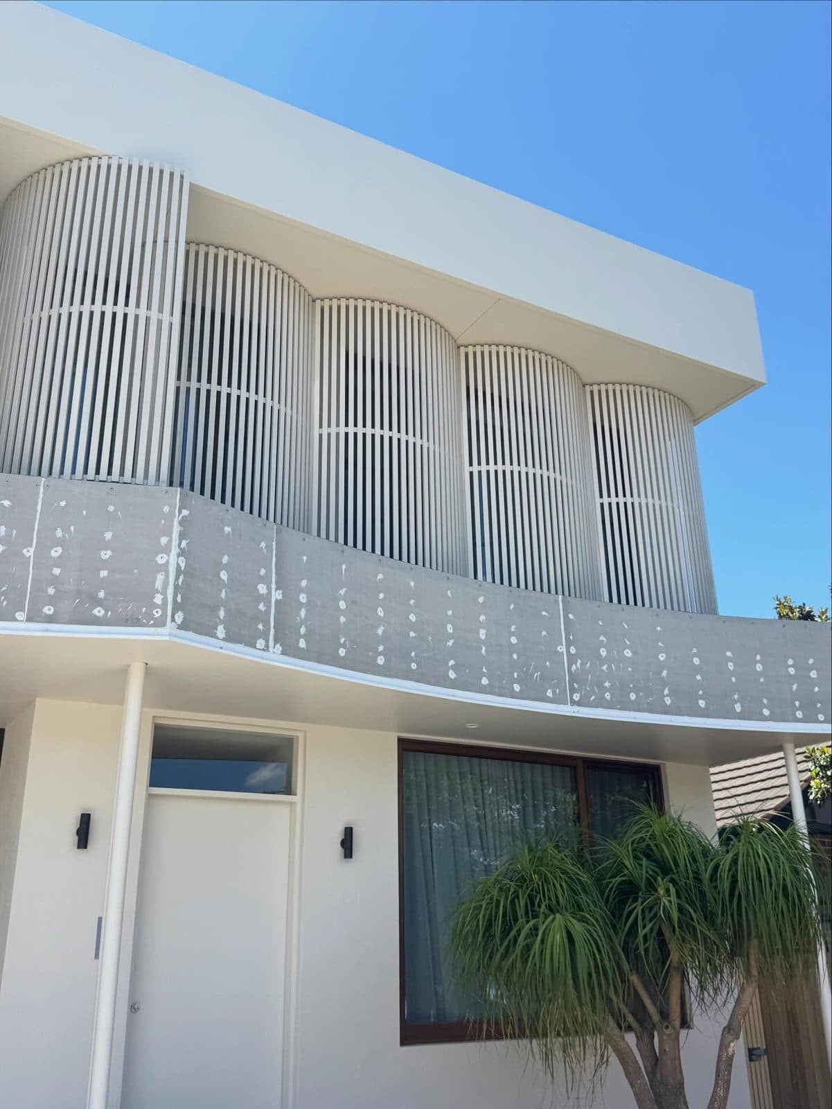 Curved white house with dark pool fence — Orton Haus