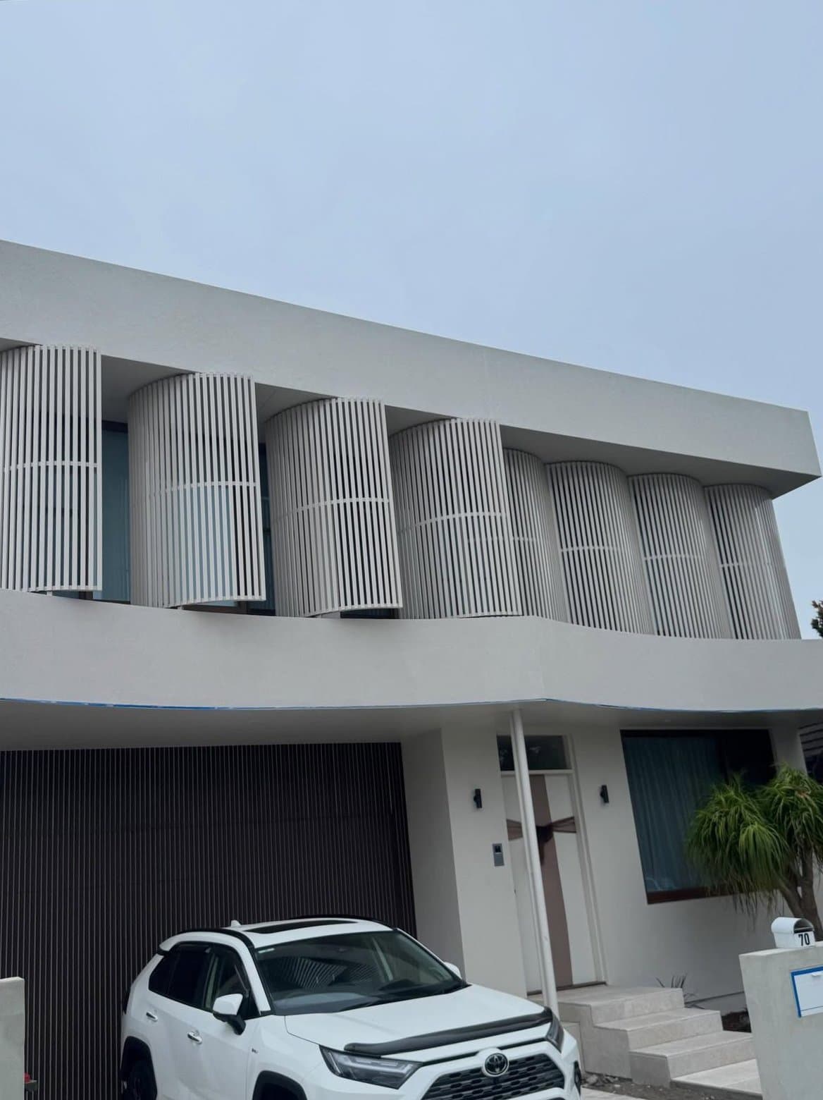White curved facade with the perforated balcony screen