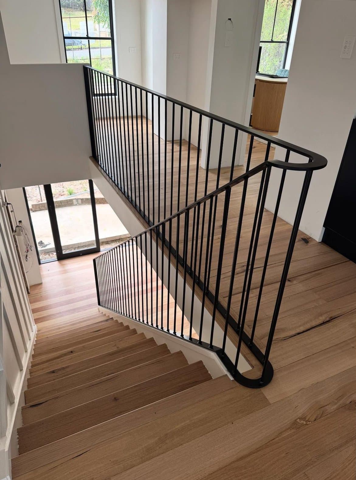 The curved black balustrade sweeping into the stair